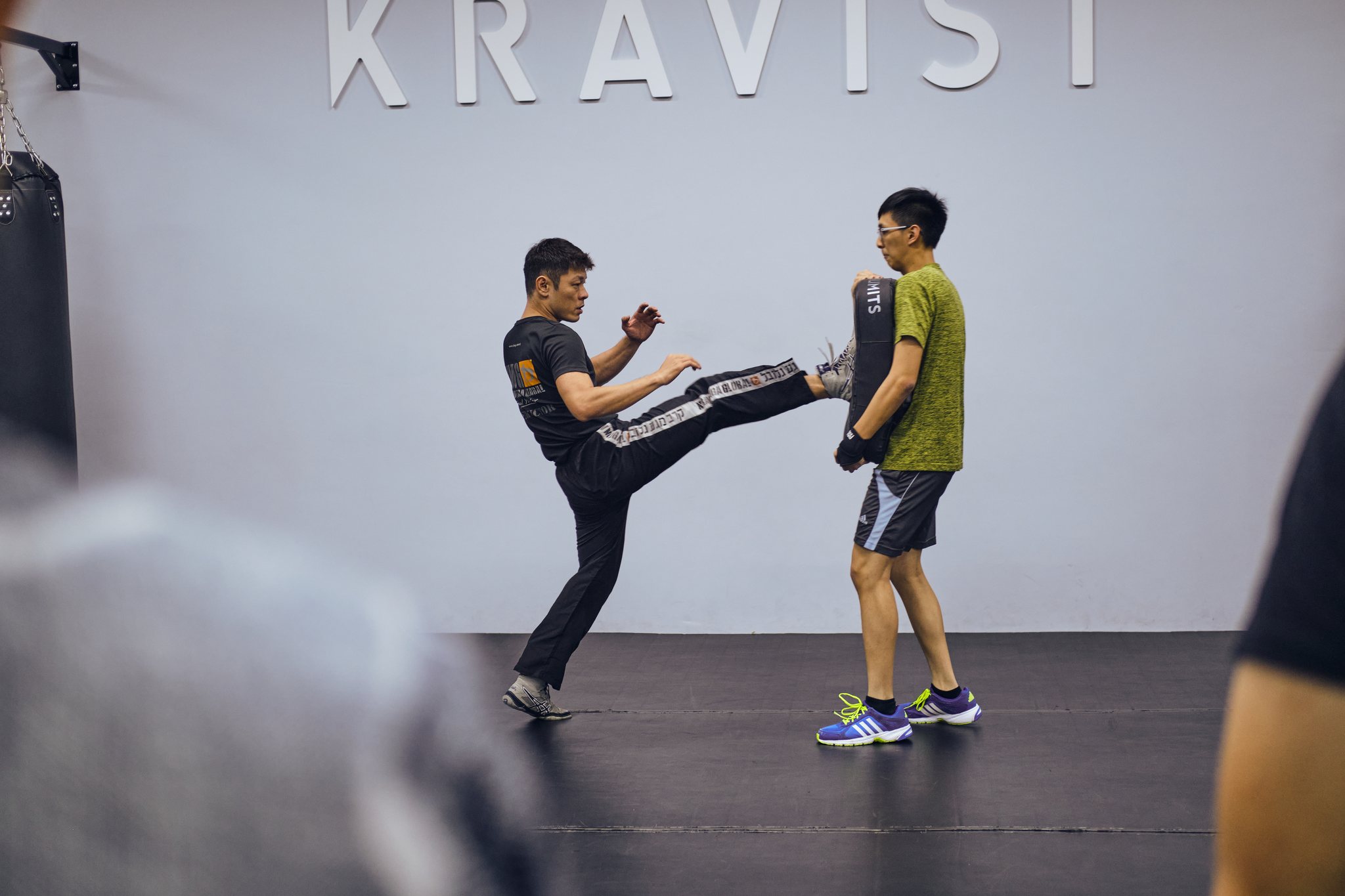 Instructor demonstrating a pad kick in adult class